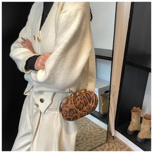 Detail of vintage leopard print crossbody bag with golden chain and metal handle on a model