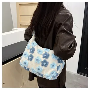 Model wearing white plush tote bag with blue flowers on a brown leather jacket