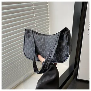 Detailed view of the monogrammed M pattern on black crescent hobo shoulder bag