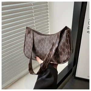 Detail view of the brown crescent hobo bag with M-letter pattern and smooth zipper