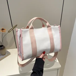 Large beige canvas tote bag with pink straps shown as a stylish handbag and crossbody bag