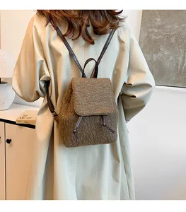 Vue détaillée de la texture en laine marron et des lanières en cuir du sac à dos