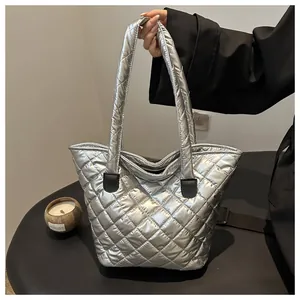 Primer plano del bolso tote acolchado plateado con detalles de cuero negro en el asa