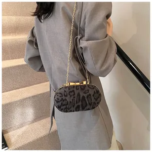 Detail of grey leopard print oval bag with a gold bow clasp and elegant chain strap