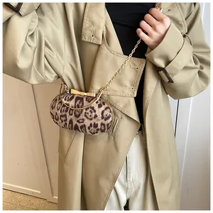 Detail of trendy leopard print handbag with golden bow hardware worn with a classic coat