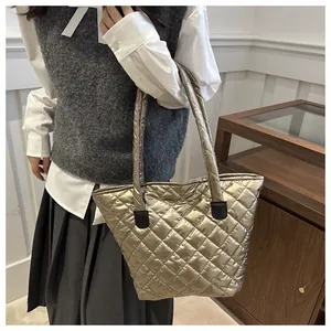 Detalle del bolso tote acolchado dorado con costuras de diamante y parches de cuero negro