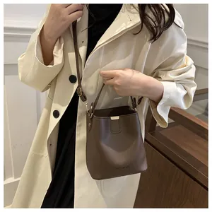 Détail du sac seau en cuir mat marron avec boucle dorée et l'inscription Fashion dessus