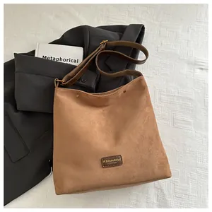Detail shot of the vintage brown suede shoulder bag showing texture and logo brand plate