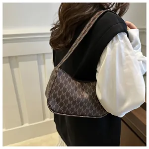 Detailed side view of the retro brown monogram shoulder bag worn by a model
