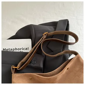 Detail of a brown matte suede hobo bag with adjustable strap and vintage copper hardware