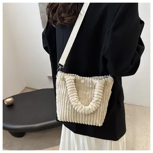 Off-white corduroy tote bag with button closure and pleated handle shown on model