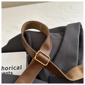Detail of adjustable brown leather strap with golden buckle on a grey suit jacket