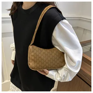 Detail of brown crescent bag with M-letter monogram and smooth synthetic leather texture