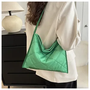 Detailed back view of a bright green quilted puffer shoulder bag worn by a model