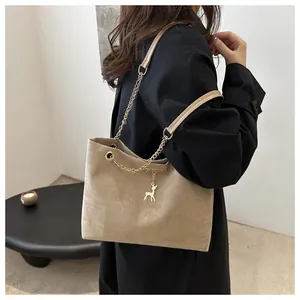 Détail du sac cabas beige en daim avec chaîne dorée et pendentif cerf en gros plan