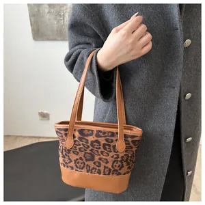 Detail showing the leopard print stitching and brown faux leather handles on the tote bag