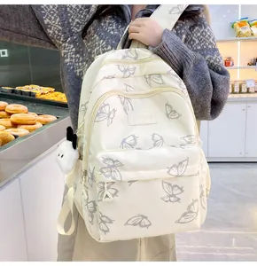 Detalle de la mochila crema con estampado de mariposas y colgante de conejo blanco