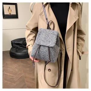 Sac à dos en laine grise avec lanières en cuir marron, porté par un mannequin en studio