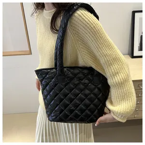 Detalle del bolso tote negro acolchado con diseño de rombos y asa de hombro ancha