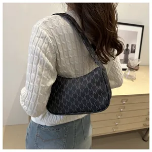 Detail of trendy crescent underarm bag with letter M print and casual shoulder strap