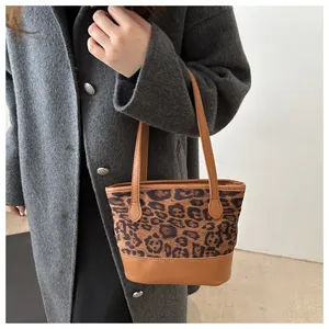 Detail view of leopard print bucket bag featuring brown leather straps on grey coat model