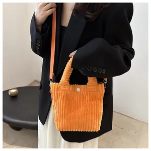 Detail view of orange corduroy crossbody bag with adjustable strap and snap button closure