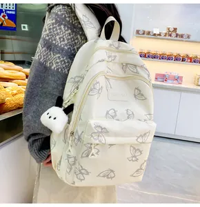 Detalle de mochila blanco roto con estampado de mariposas y colgante de peluche