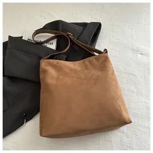 Detailed close-up of brown suede square tote with vintage rivets and wide strap