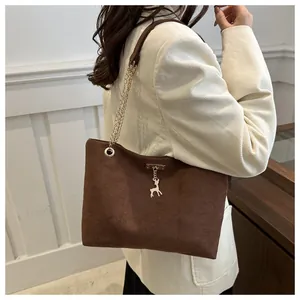 Détail du sac cabas en daim marron avec pendentif cerf doré et bandoulière en chaîne