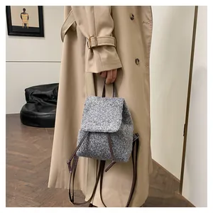 Détail d'un sac à dos en laine grise avec bretelles en cuir porté par un mannequin