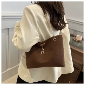 Détail du sac bandoulière en daim marron avec pendentif cerf et chaîne dorée
