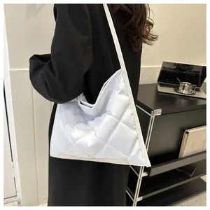 Close-up of quilted white puffer shoulder bag with large diamond stitching and soft texture