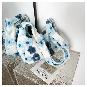 Detail of floral plush tote bag with blue flowers near an art book and mirror