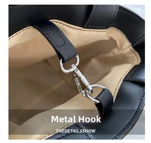 Detail of silver hardware lobster hook and beige twill lining inside the black tote bag