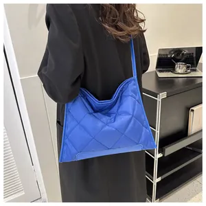 Detail of royal blue quilted shoulder bag with large diamond lattice and glossy nylon finish