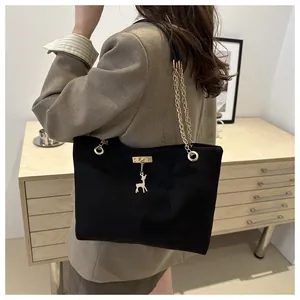 Détail du sac cabas en daim noir avec bandoulière en chaîne dorée et pendentif cerf