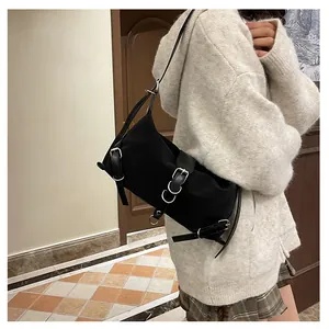 Detail view of a black techwear shoulder bag with silver buckles shown on a model