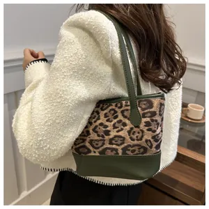 Detailed view of leopard print tote bag with green leather trim shown on a model