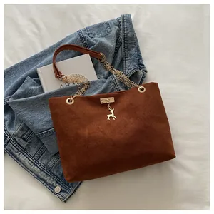 Gros plan détaillé d'un sac cabas en daim marron avec chaîne dorée et pendentif cerf