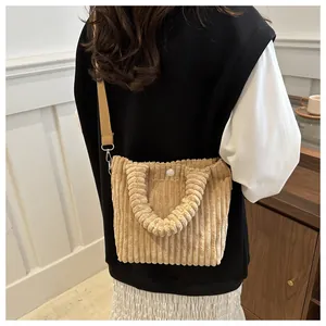 Close-up of beige corduroy crossbody bag texture with button detail and fabric strap
