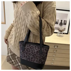 Leopard print拼接tote bag with black leather handles shown on a beige knitted sweater