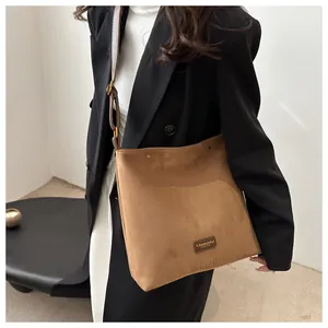 Brown faux suede crossbody bag detail showing gold-tone hardware and chic leather logo tag