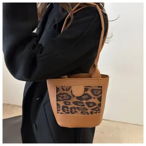 Close-up of vintage brown leather tote bag with leopard print panel and top handles