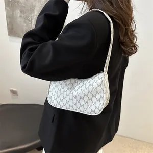 Minimalist white crescent underarm bag with all-over grey M pattern shown on a model