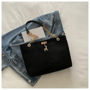 Détail du sac cabas noir avec bandoulière chaîne dorée et pendentif cerf élégant