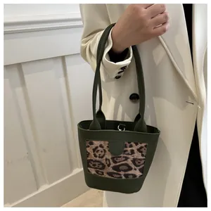 Detail of vintage green leather tote bag with leopard print panel held by a model