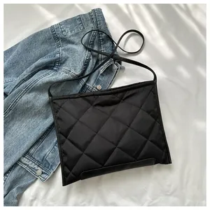 Close-up of black quilted nylon bag with rhombus pattern on denim jacket background