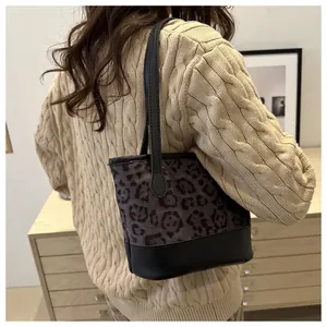 Close-up of a leopard print patchwork hobo bag on shoulder with beige knit sweater