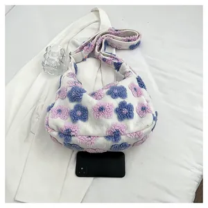 Top view of plush floral hobo bag with pink and blue 3D flowers on soft white fabric