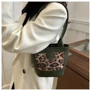 Detail of dark green leather bucket bag featuring a leopard print panel and slim handle